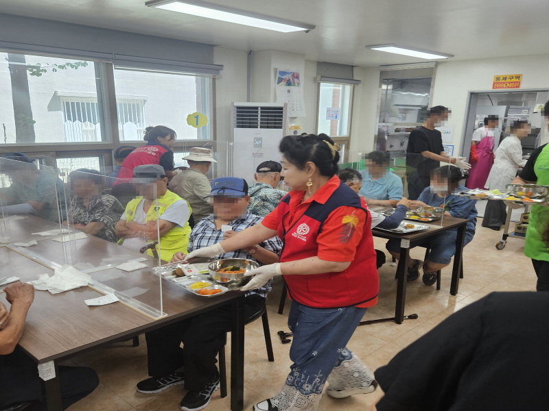목련로터리클럽 자원봉사자가 어르신들에게 식사가 담긴 식판을 직접 나누어주는 장면
