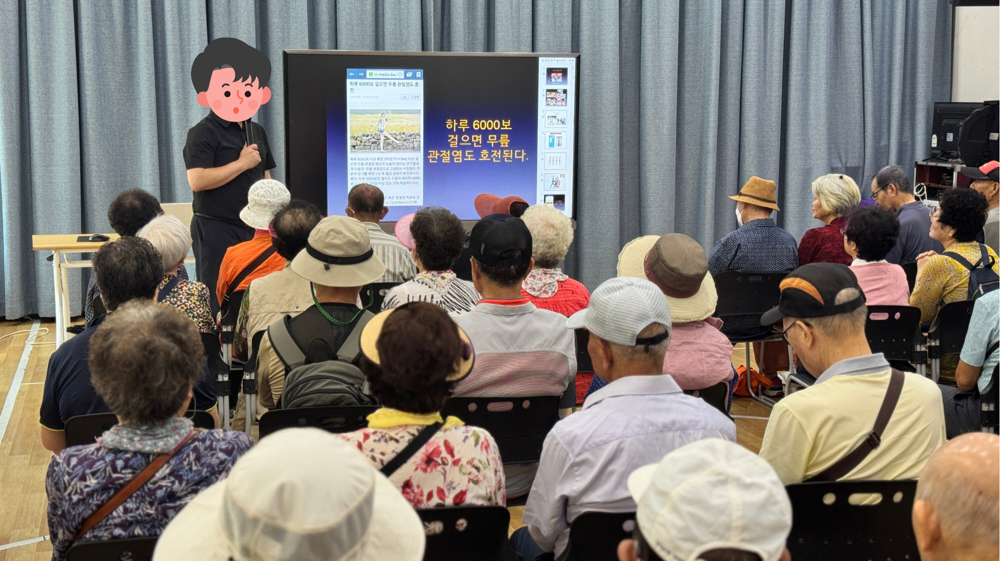 강당에서 건강교육이 열리고 있으며, 강사가 앞에서 마이크를 들고 스크린을 가리키며 설명하고 있고, 참가자들이 의자에 앉아 교육 내용을 집중해서 듣고 있습니다. 스크린에는 ‘하루 6000보 걸으면 무릎 관절염도 호전된다’라는 문구가 보입니다