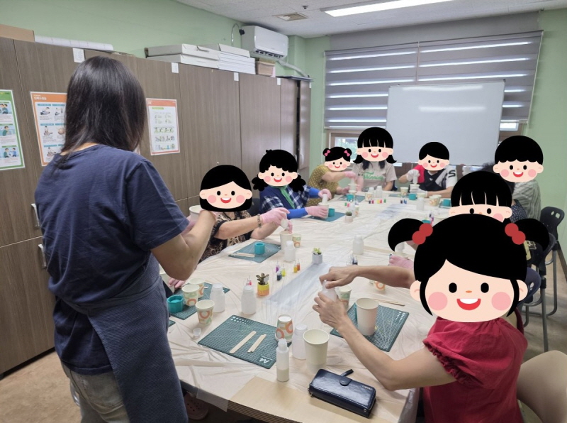 평생교육 프로그램 활동. 여러 명의 참여자가 교실 책상에 둘러앉아 강사의 안내를 받으며 만들기 체험을 하고 있다. 책상 위에는 종이컵, 도구, 재료들이 놓여 있다.