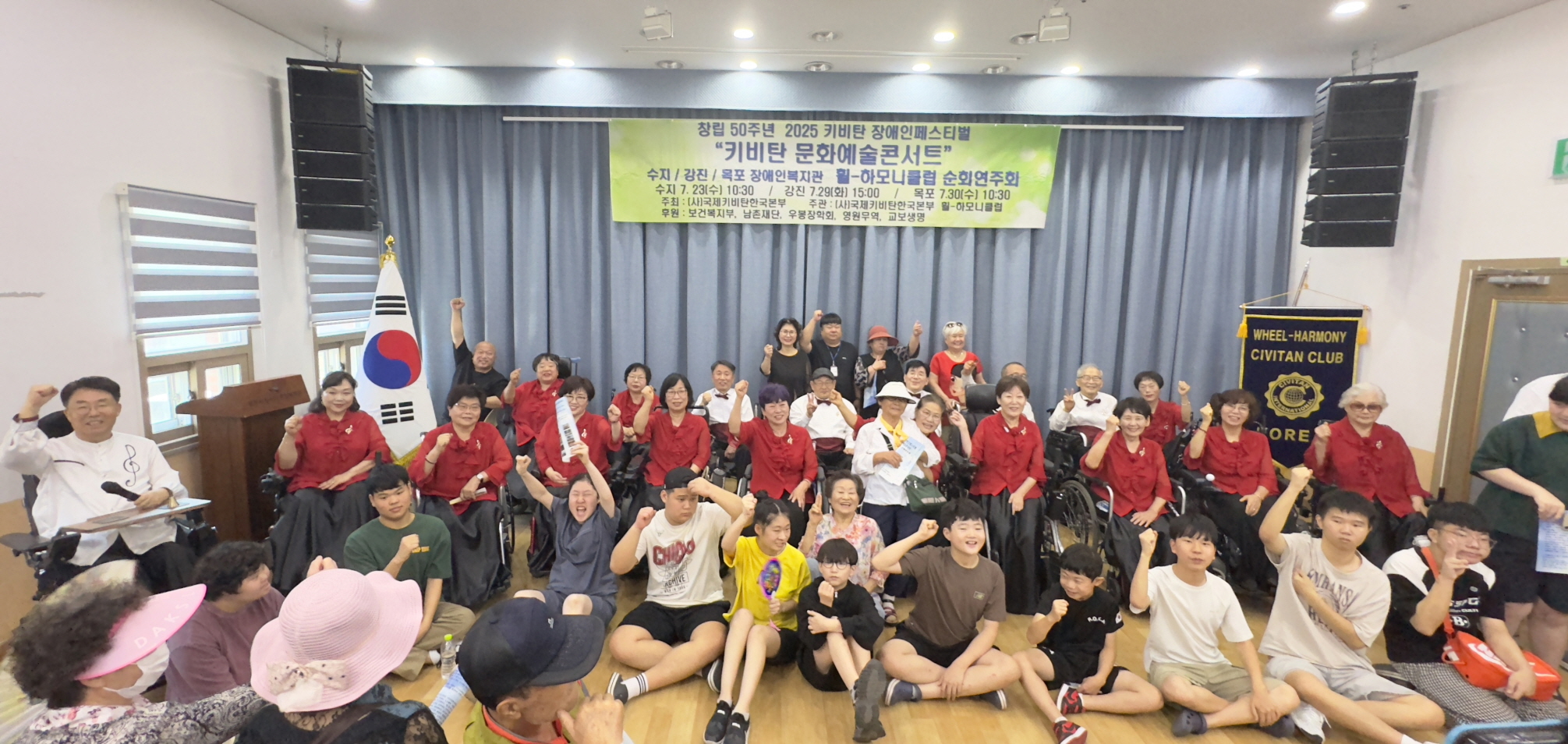 공연을 마친 뒤 휠-하모니클럽 단원들과 장애인 관객들이 함께 단체사진을 찍으며 손을 들어 응원의 포즈를 취하는 장면
