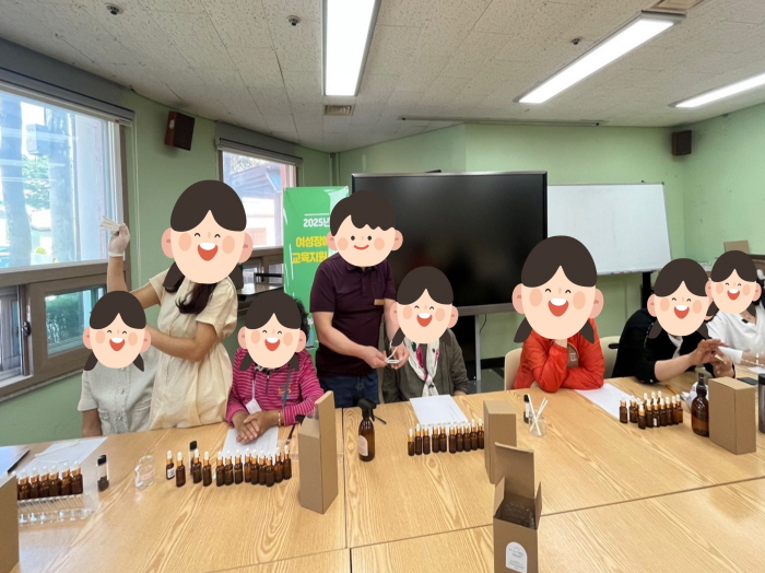 여성 장애인들이 책상에 둘러앉아 아로마 향수 만들기 프로그램에 참여하는 모습. 작은 유리병과 향료를 직접 다루며 시향을 하고 있다.
