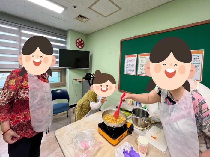앞치마를 착용한 여성 장애인들이 조리대에서 냄비와 조리도구를 사용해 음식을 만드는 장면. 한 참여자가 국자를 들고 요리를 저으며 체험하고 있다.