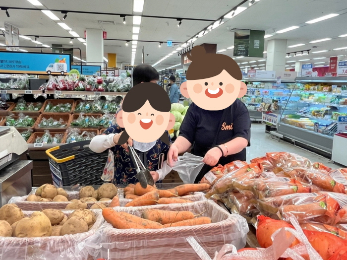 여성 장애인들이 대형마트 채소 코너에서 당근과 감자를 직접 고르며 장바구니에 담는 모습. 요리 실습을 위한 장보기 활동을 하고 있다.