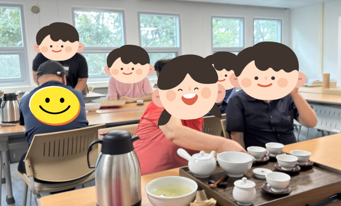 목포대학교 평생교육원 강의실에서 복지관 이용자들이 다도 프로그램에 참여하고 있다. 책상 위에 찻잔 세트와 주전자가 놓여 있고, 참여자들이 차를 따르고 맛보며 전통 다도 문화를 체험하는 모습이다.