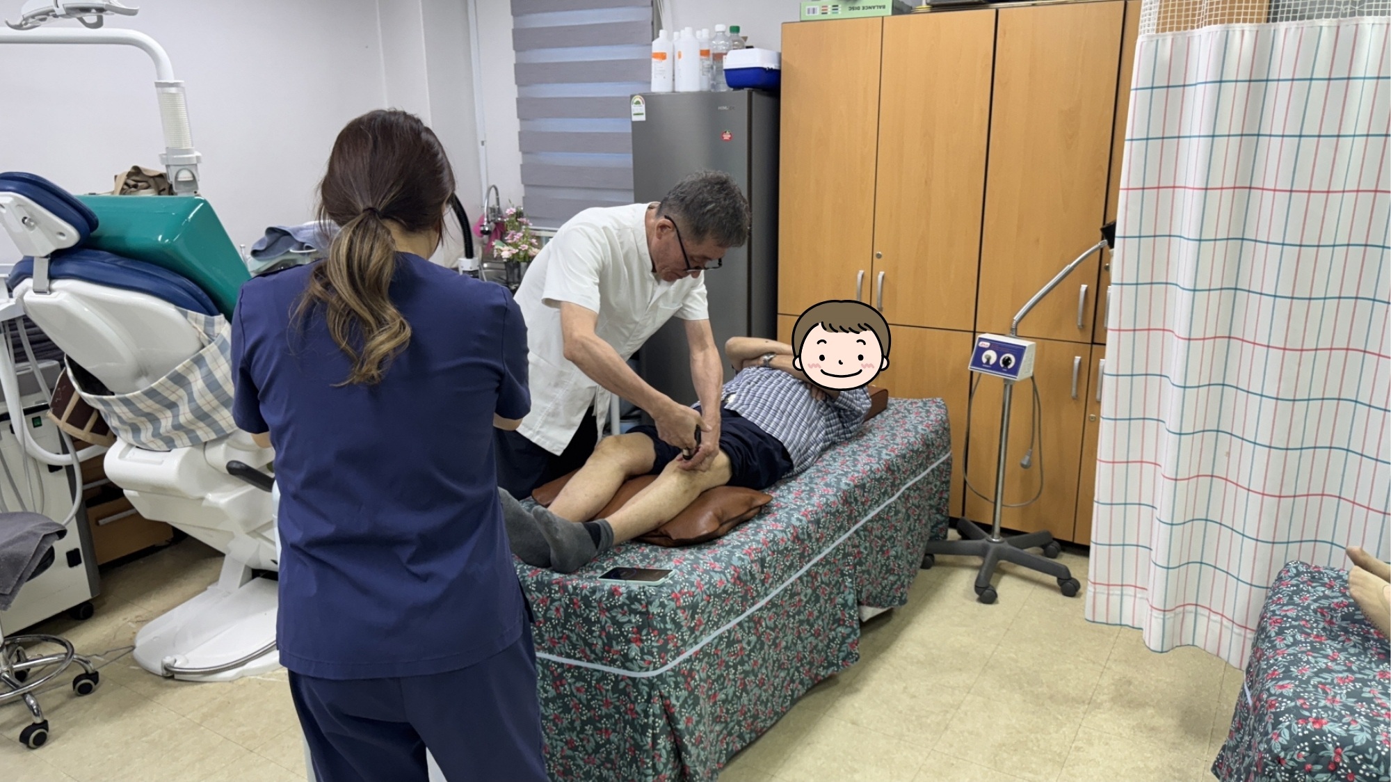 의료봉사자가 누워 있는 장애인 이용고객의 다리를 잡고 진료와 치료를 진행하고 있다. 옆에서는 간호사가 돕고 있다.