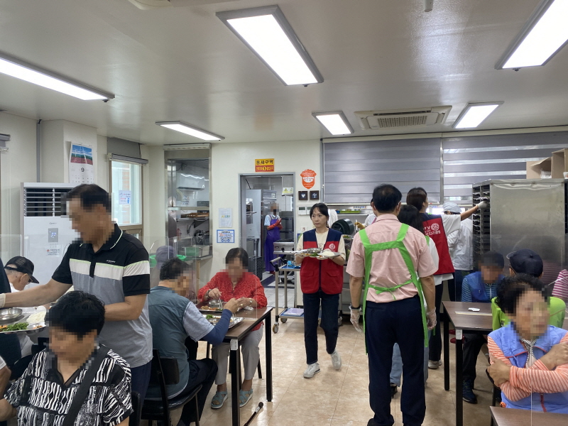 목련로터리클럽 봉사자들이 식당 안에서 음식을 전달하고, 고객들이 식탁에서 식사를 하고 있는 모습