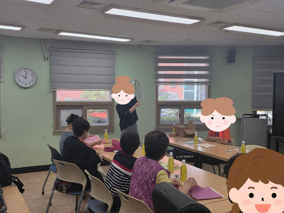 강사가 앞에서 시범을 보이며 참여자들에게 재료를 설명하고, 책상에 앉은 참여자들이 집중해서 바라보는 모습