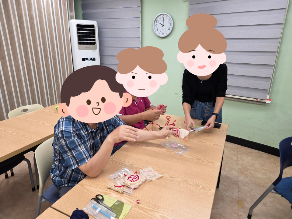 참여자들이 강사와 함께 끈을 이용한 공예 활동을 배우며 웃으며 만드는 모습