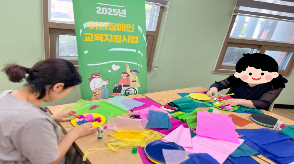 2025년 여성장애인 교육지원사업 배너 옆에서 두 명의 여성장애인이 색색의 한지와 도화지를 활용해 꽃 모양 공예 작품을 만들고 있는 모습.