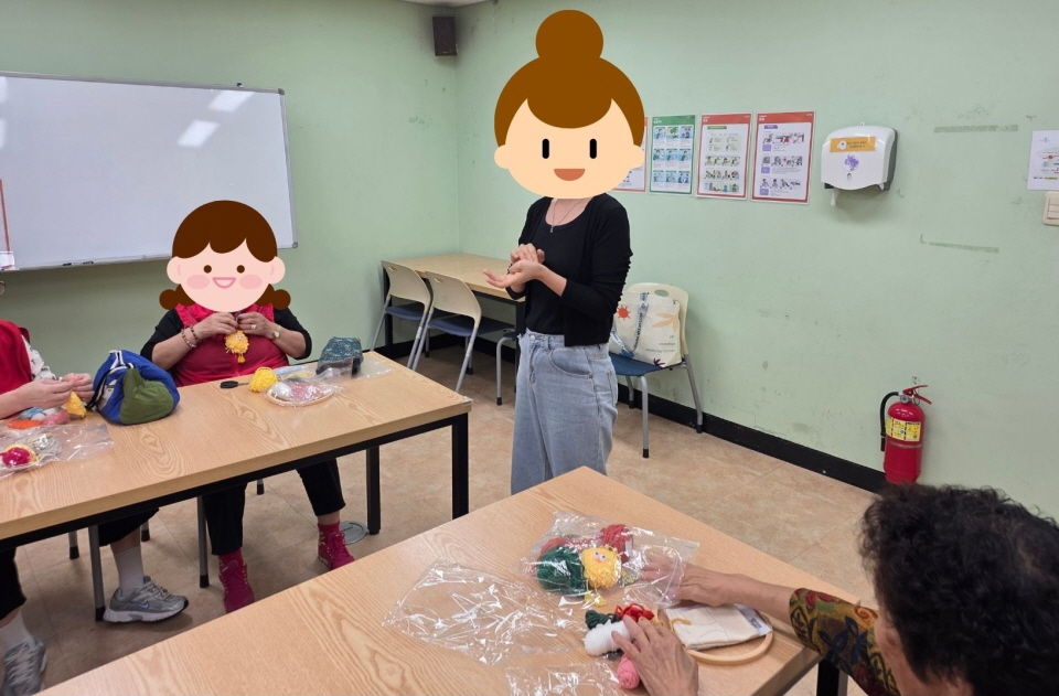 복지관 프로그램실에서 펀치니들 공예활동이 진행되고 있음. 참여자들이 바늘과 실을 사용해 천 위에 무늬를 수놓는 작업을 하고 있으며, 강사가 제작 방법을 안내하며 함께 완성도를 높이는 모습임.