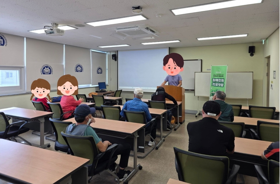 ‘원예치유힐링 프로그램’ 현수막이 걸린 프로그램실에서 강사가 단상에 서서 강의를 진행하고 있음. 이용고객들은 책상에 앉아 강사의 설명을 경청하며 화면을 바라보고 있음. 공간은 밝고 차분한 분위기이며, 교육용 스크린과 컴퓨터가 준비되어 있음.