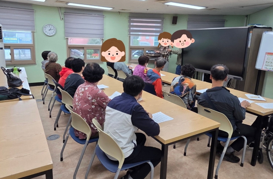 복지관 프로그램실에서 음악치료 프로그램이 진행되고 있음. 이용고객들이 음악 재생 기기에서 흘러나오는 음악에 맞춰 리듬악기를 연주하거나 노래를 따라 부르고 있음. 강사는 이용고객들의 참여를 독려하며 즐겁고 활기찬 분위기를 이끌고 있음.