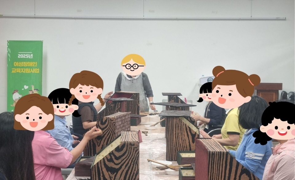 ‘2025년 여성장애인 교육지원사업’ 현수막이 걸린 강의실에서 목공예 수업이 진행되고 있음.   참여자들이 나무 책꽂이를 직접 만들며 사포질과 도색을 하고 있고,   앞쪽에서는 강사가 작업 과정을 설명하며 시범을 보이고 있음.   모두 진지하게 작업에 집중하는 모습임.