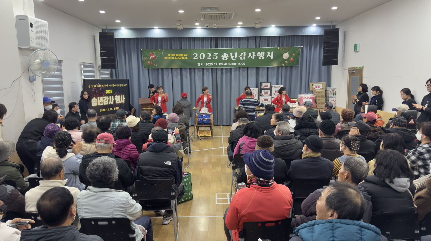 2025 송년감사행사에서 난타 공연이 무대에서 진행되고, 북과 타악기를 두드리는 힘찬 동작과 함께 객석을 가득 채운 이용고객들이 무대를 바라보며 관람하고 있다.