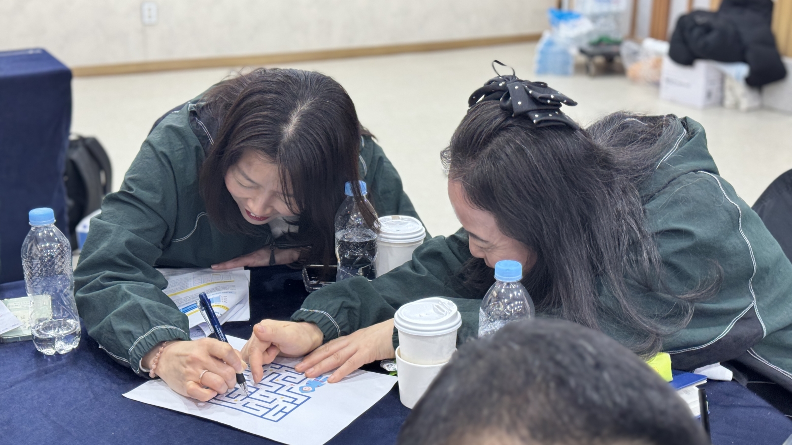 직원들이 MBTI 기반 고객소통 전략의 일환으로 팀워크를 다지는 미로 찾기 활동지에 집중하고 있는 근접 촬영 사진